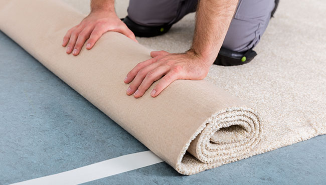 Worker's Hands Rolling Carpet At Home | Key Carpet Corporation